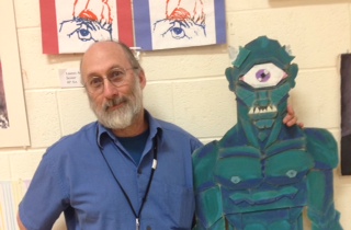 George Hancin teaches Art I and poses with artwork in the yearly Art Show.