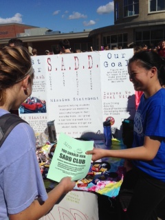 Sophomore Jordan Young passes out a flyer for the SADD club to fellow sophomore, Jackie Lambert.