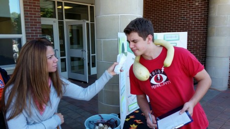 Junior Alex VanAntwerp shows off his fig necklace and tomato for the environmental club.