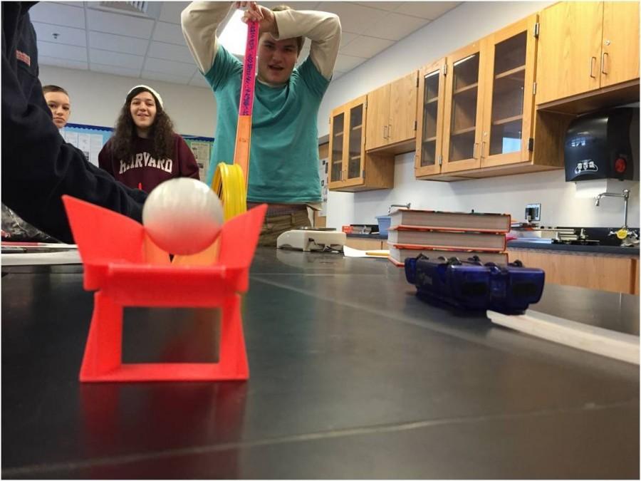 Junior Parker Lescalleet participates in a demonstration during Physics class as juniors Francesca Bellizi and Alexa Delapena look on. 