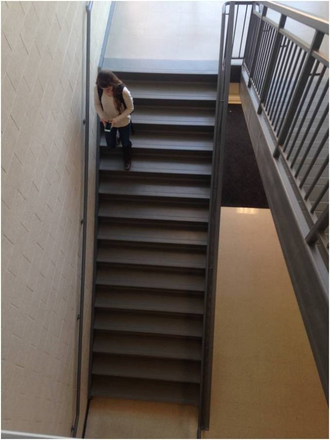 A student walks down a D-hallway stairwell on her way to class. 
