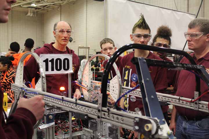 Team 1100 members adjust their robot during competition.