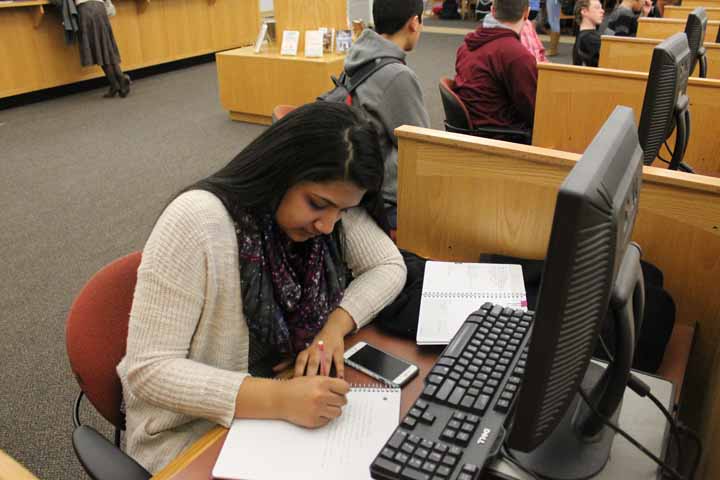 Sophomore Sumati Rangaraj writes in a notebook while using one of the library computers.