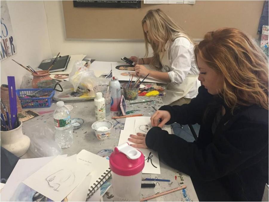 Focused on their elaborate paintings, seniors Kate Massucco and Mackenzie Hostage sit in their everyday  corner while watching an episode of Grey’s Anatomy on their cell phone in George Hancin’s AP Art Class.