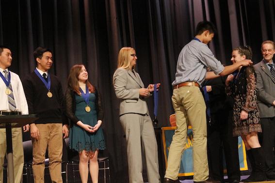 NHS member senior Kevin Shi places the traditional medallion over inductee junior Kelly Slovens head. 