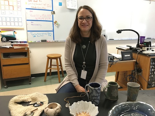 Chemistry teacher Catherine Burchat poses with her works of pottery.