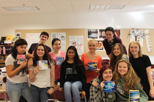 The She-Hawks gather around various feminine hygiene products that were donated over the three-week collection period that was aimed at helping homeless women get the tampons and pads they need. Club members delivered the donated products to the Worcester YWCA. 