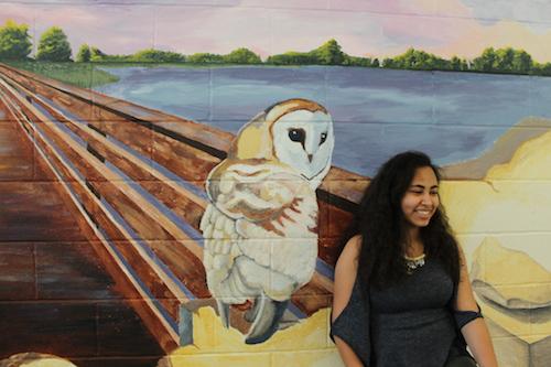Sophomore Nadine El Nesr poses in front of the mural in the cafeteria.