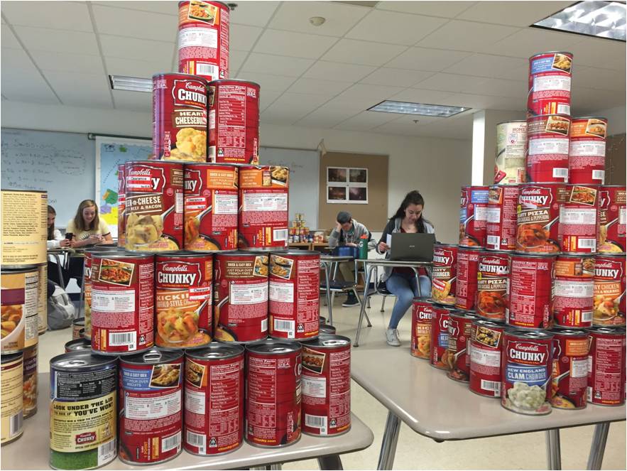 Students work, laugh and sleep in the midst of all the soup cans they have collected for the food drive.