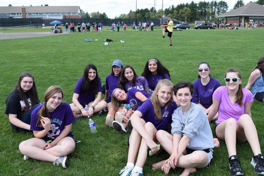 A group of freshman girls sit on the field and enjoy their time together on carnival day.
