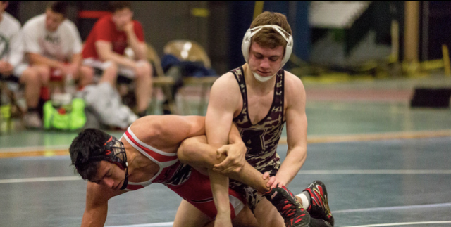 Junior Drew Cozzolino pins down his opponent in a wrestling match. 