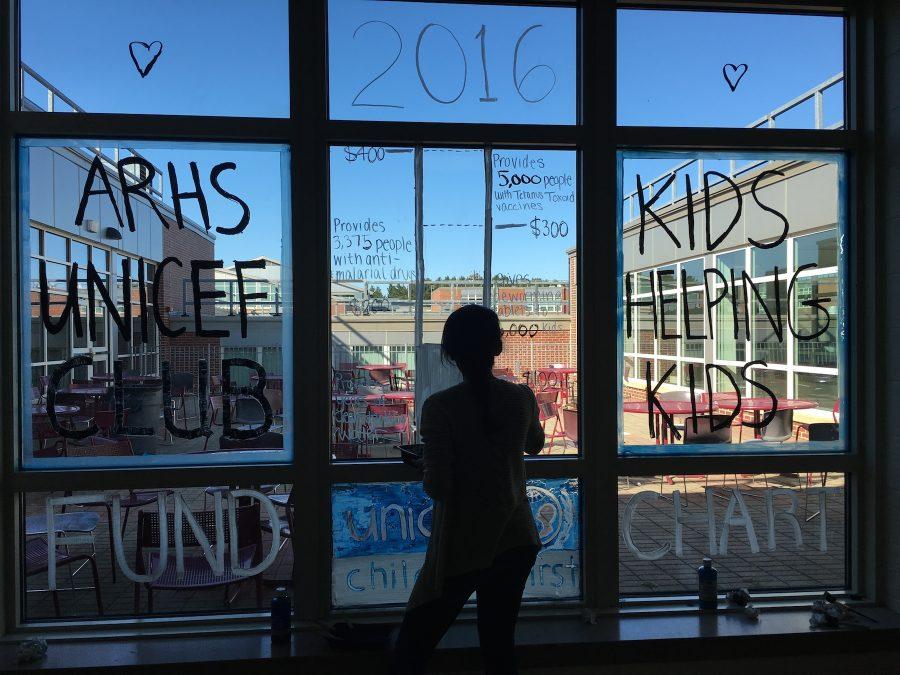 Sophomore and secretary Jyothi Polackal paints a window in the cafeteria for the Unicef fund chart.