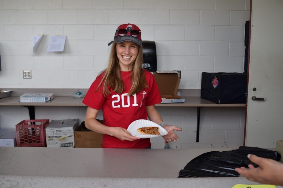 Junior Gretchen Forbush helps at the concession stands by handing out pizza.