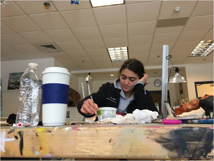 Senior Elena Avradopolous concentrates as she paints a face using watercolors in AP Art.