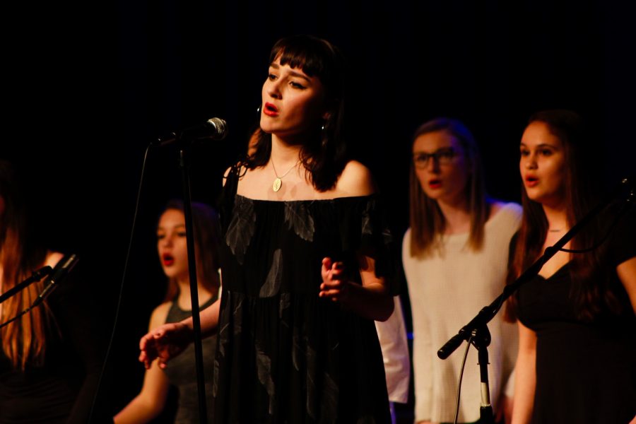Senior Chloe Bernier leads her a cappella group, Ladies First, in their rendition of Black Horse and a Cherry Tree by KT Tundtall at Acapocalypse on March 13. 