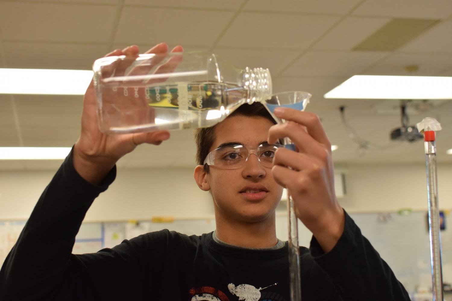 During a titration lab in Chemistry class, Sophomore Armaan Munsiff pours sodium hydroxide into a burette.