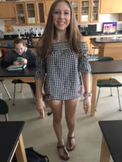 Wearing an off-the-shoulder checkered top with some red detailing on the side, freshman Lydia Magiannis fashions her outfit with a cute pair of Birkenstock sandals and some layered necklaces, perfect for a nice summer day. 