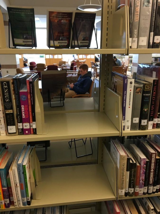 The library is usually full of people working hard on schoolwork and getting ahead in classes. A senior is found relieving the stress listening to movies in a reclined chair.