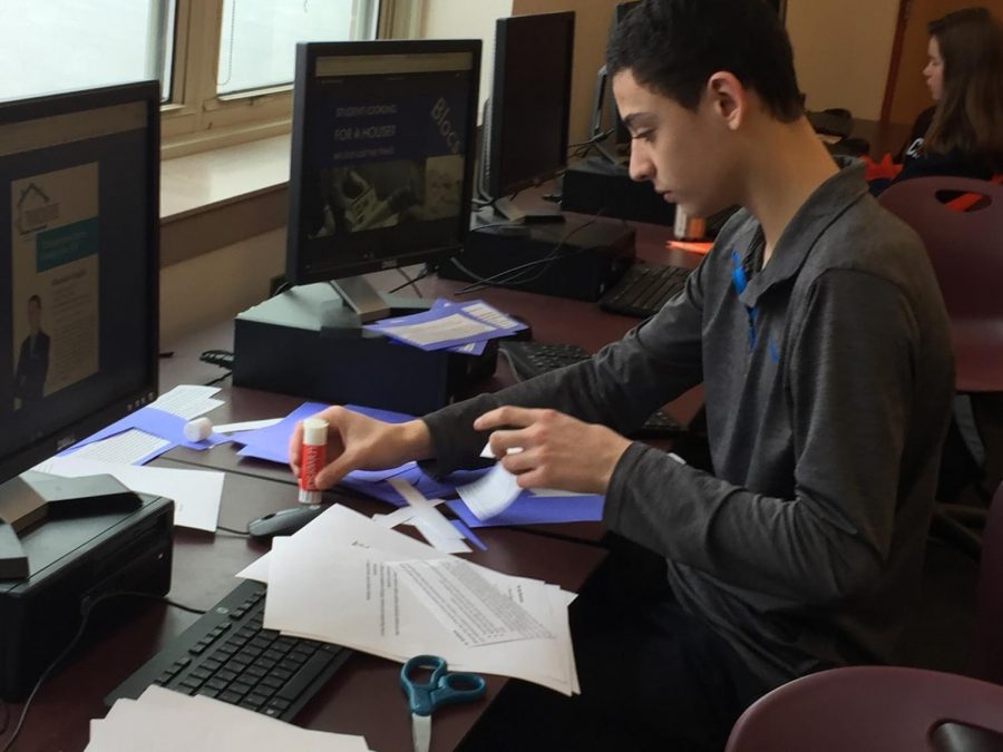 Working hard on his Business Fundamentals project, freshman Alejandro Foglia is gluing papers down for his project. 