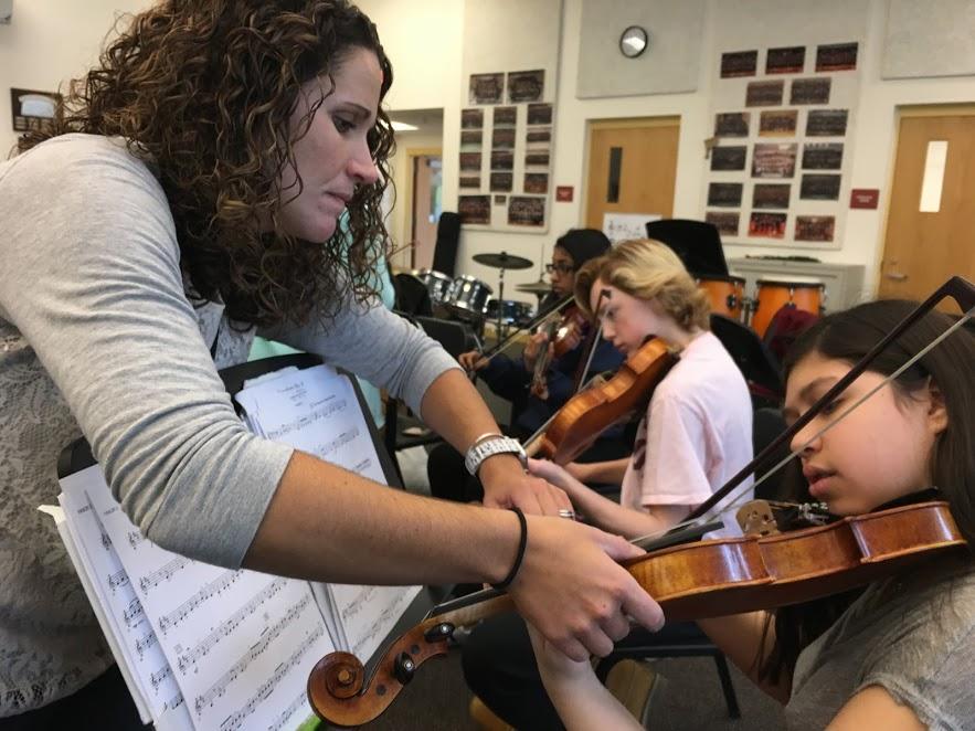Freshman Gabriela Requena learns a new technique with the help of teacher Amy Collins as they prepare for Pops Night which will be held on May 30.