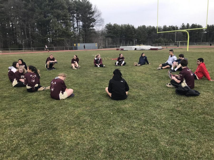 Unified Track friends stretch together on the football field during their pre meet warmup.