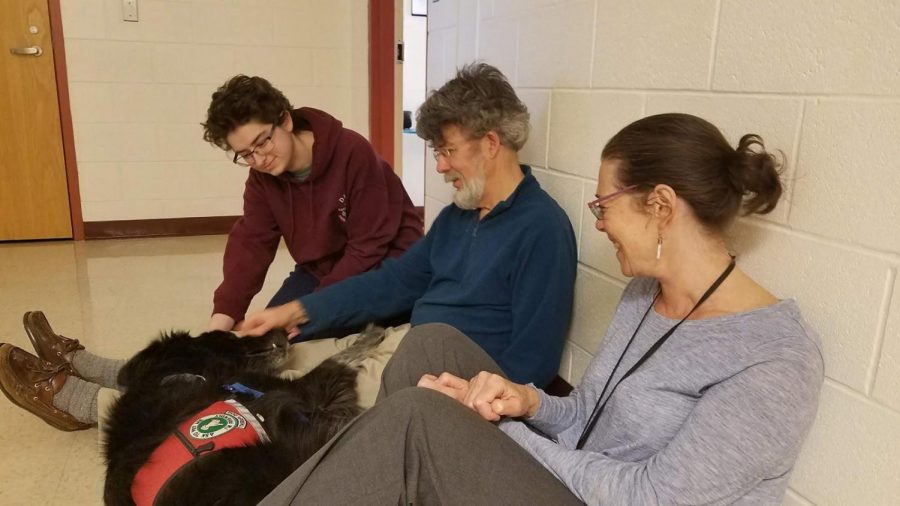 Senior Carlyn Schwingbeck, Ed Harrow of Pets and People, and special education teacher Beth Mintz play with Tucker the therapy dog. Mintz and Scwingbeck have worked with the Pets and People organization to bring therapy dogs into Algonquin to provide relief for students.