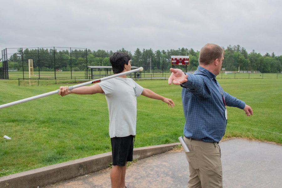 Unified track coach Kevin Hausmann shows a unified track member how to correctly throw the javelin.