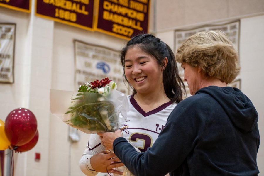 Senior girls volleyball captain Andrea Jiang smiles as she is handed flowers by her coach during the pregame celebration to honor the seniors on the team. Algonquin defeated Wachusett 3-0 on Oct. 25.