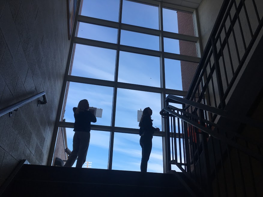 During art class, freshmen Lilia Treviño and Amanda Brossi work on an abstract portrait project, using the backlit windows to trace parts of a photo. 