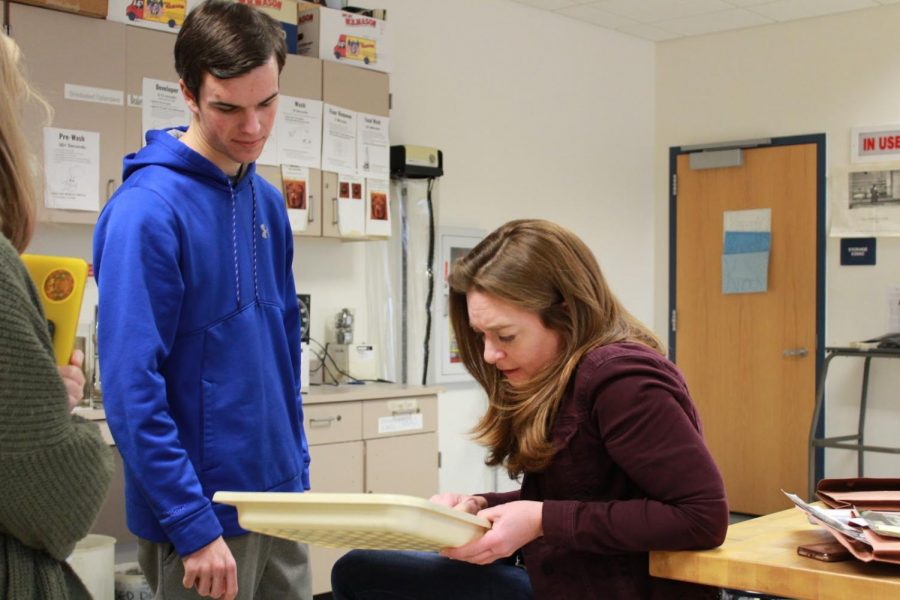 Fine and Performing Arts teacher Michelle Sheppard looks at senior Garrett Goodney’s print and tells him what he should do next time he goes into the dark room.