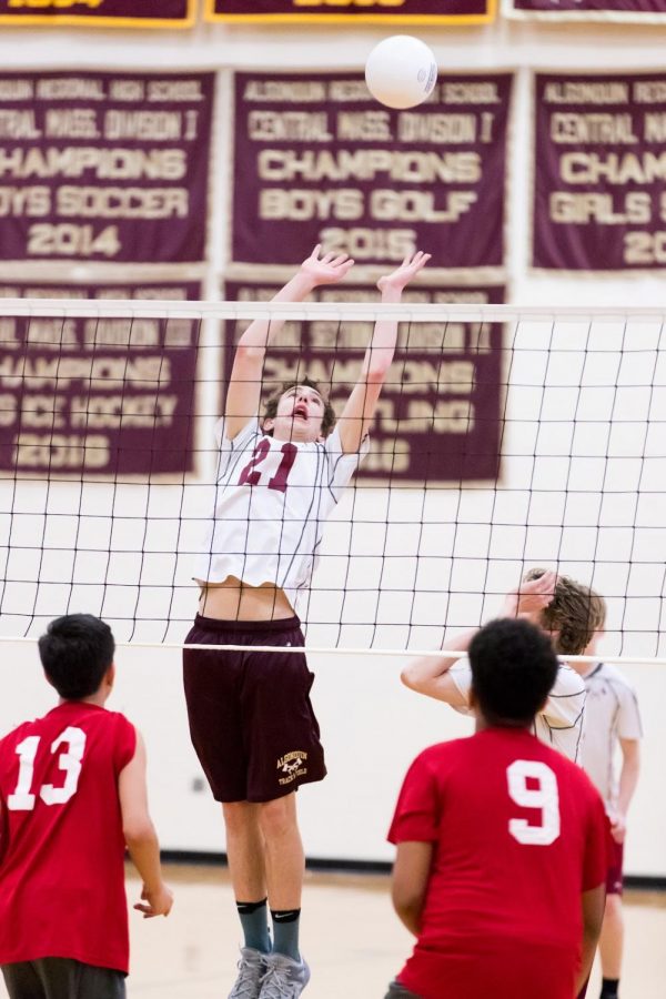Senior Colin Kerrigan reaches high above the volleyball net to reach the ball and gain a point for his team.