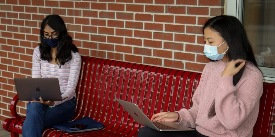 Sitting outside the rotunda, juniors Cynthia Rajeshkanna and Melissa Dai go over potential dates for tutoring.