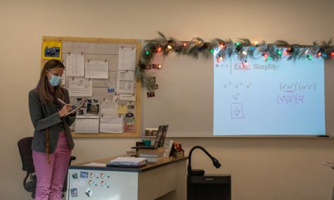 Math teacher Mary Rose Steele writes down solutions to exponential expressions on the board during a hybrid day which allows for in person learning.