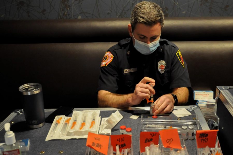 Ashland Firefighter John Brovelli fills syringes with the Moderna COVID-19 Vaccine at the MetroWest Regional Vaccination Clinic.