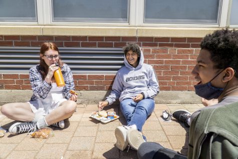 Freshmen Taylor Queenan, Hunter Lopez and Jayden Edwards chat while eating their lunches. As public areas reopen, many people are able to go outside without a mask for the first time in a while.