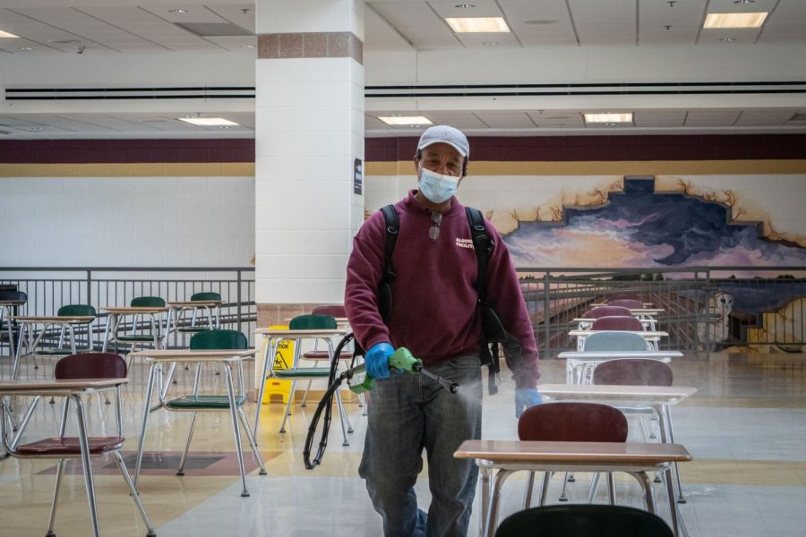 ARHS facility member Jon Souza flashes a quick smile through his mask while sanitizing the cafeteria.