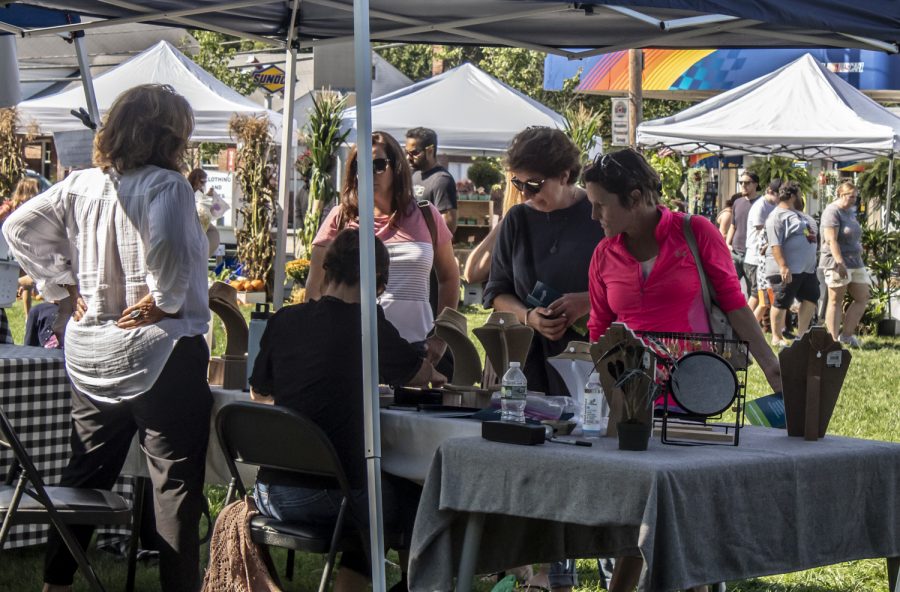A group of women look at some jewelry at one of the many vendor tents at the Farmers Market on the Town Common. 