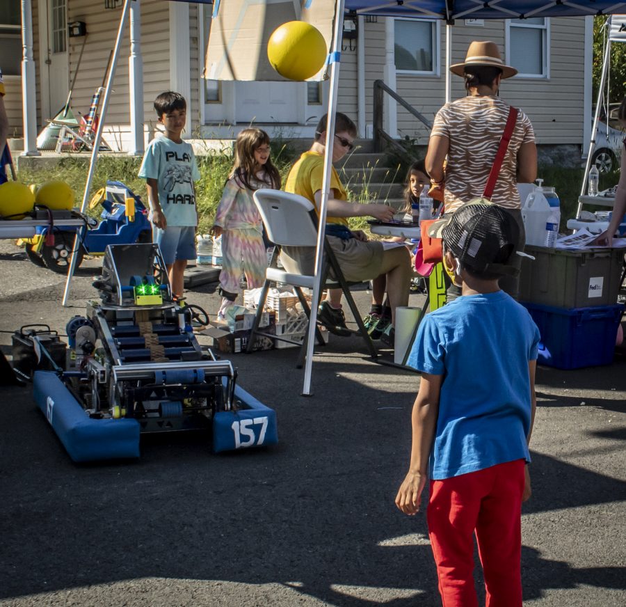 A boy tries to catch a ball from a robot at a tent at the Applefest Street Fair. 