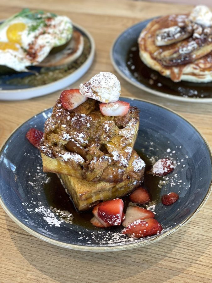 The Brioche French Toast Square is garnished with cinnamon + honey butter and strawberry add-ons. 