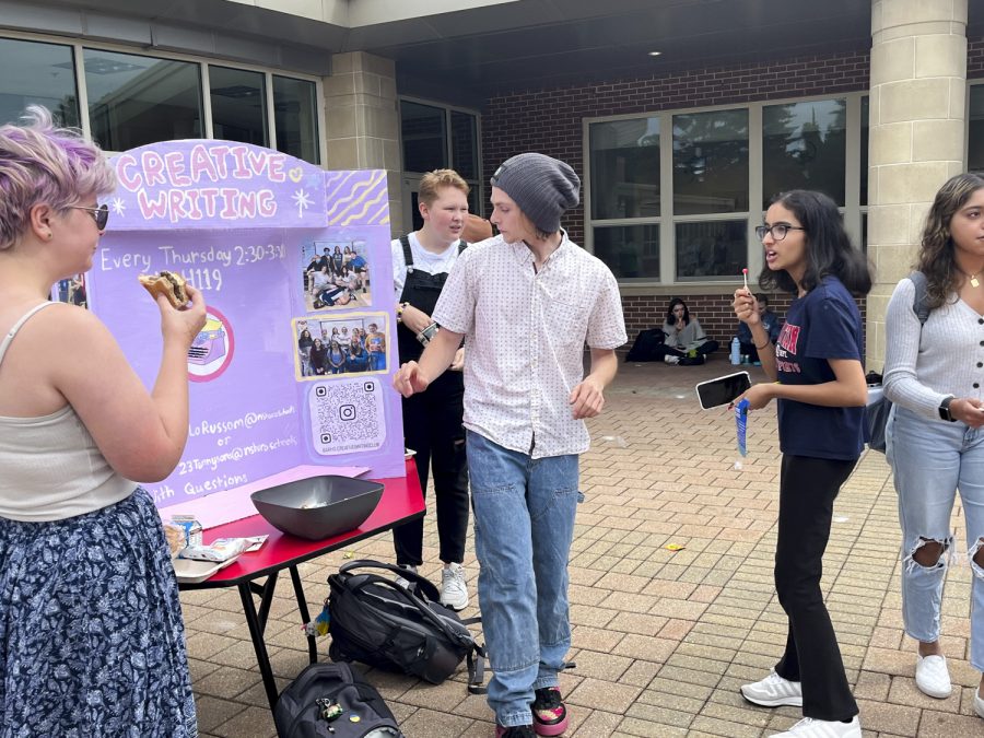 Seniors Marianna Lorusso and Alex Rinekey explain to passing students what the Creative Writing Club is all about during the Activities Extravaganza held during all three lunches on Wednesday, Sept. 21, 2022.