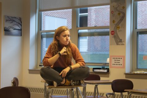 Senior class president Sarah Coldwell sits on a desk during a Senior Steering Committee meeting listening to her peers share their opinions on new ideas.