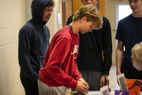 Sophomore Nathan Meschisen gives a student change for their Boo Bag, a Halloween fundraiser.