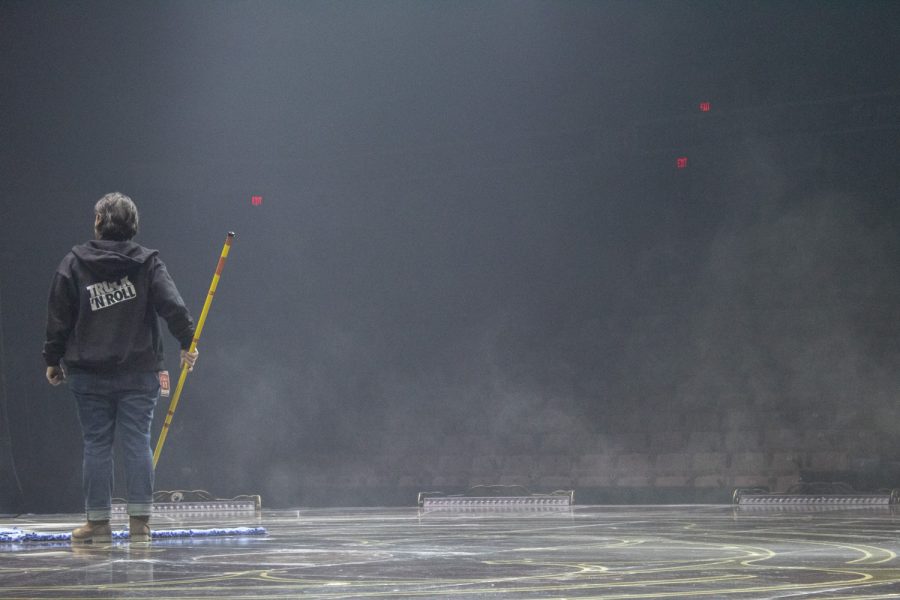 A member of the crew cleans up chalk on the stage after a warmup of artists practicing on the bars in the show Corteo by Cirque du Soleil.