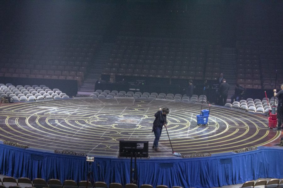 A crew member of the Cirque du Soleil cleans up chalk on the stage after performers practiced for the scene “Tournik.”