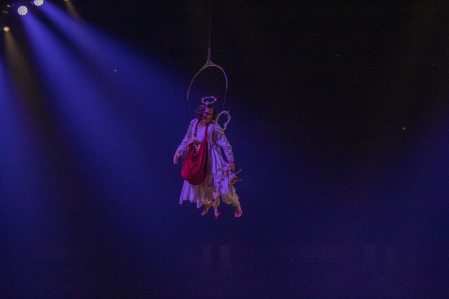 An angel flies across the stage throwing stuffed animals at the performers below for the show Cirque du Soleil.