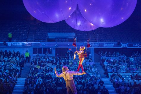A performer playing the character Valentyna hangs from balloons while walking across another performers arm in Cirque du Soleils show, Corteo, at the Worcester DCU Center.