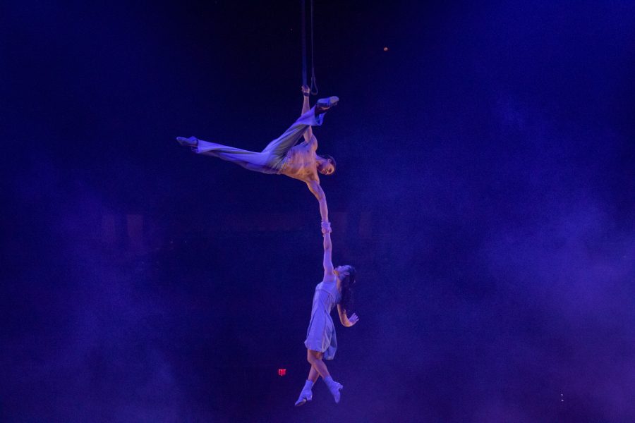 Two arial contortionists wrap their bodies around the silk rope as they hang on to one another in Cirque du Soleil.
