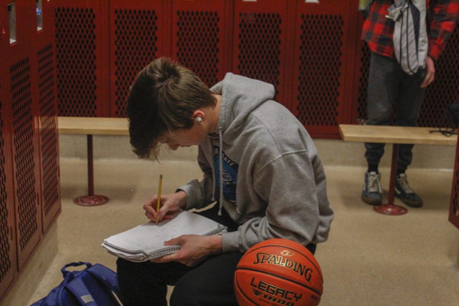 Sophomore Jonah Gould works on his homework in the locker room before his meet on Dec. 21.