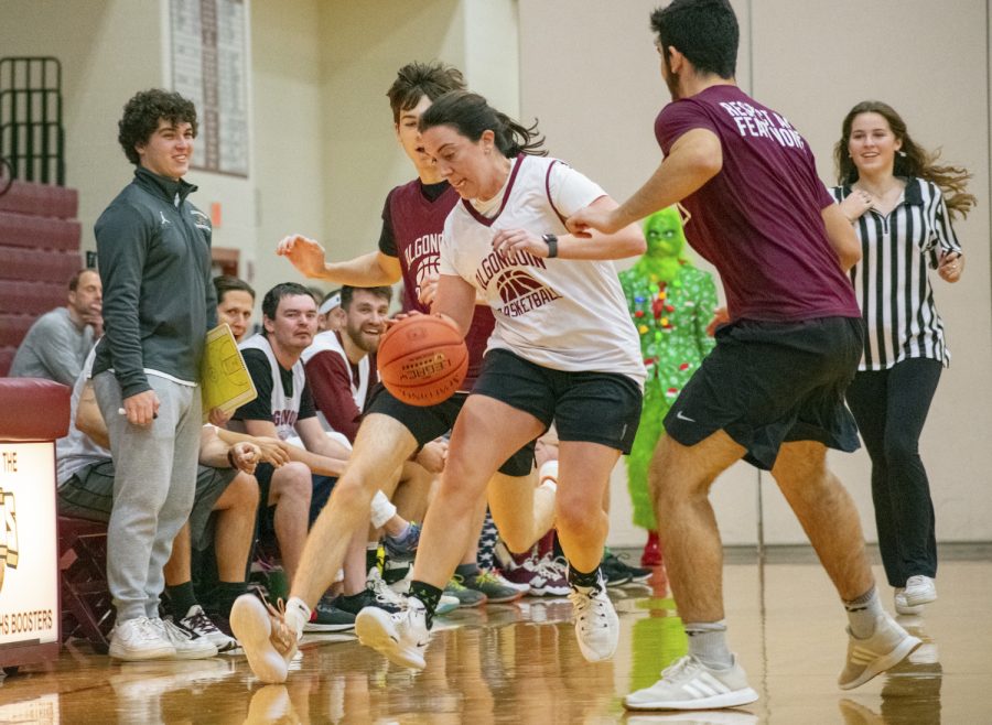 Health and Fitness teacher Kristen Morcone dribbles past two defenders in the Student vs Faculty game on Dec. 23, 2022 as Faculty team coach senior Andrew Hodge looks on. The faculty won the game.