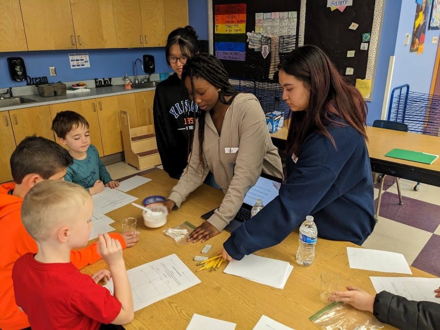 ATOMS club members sophomores Ingrid Yang, Jane Olaniyan and Anola Omiecki help elementary students with science activities. 